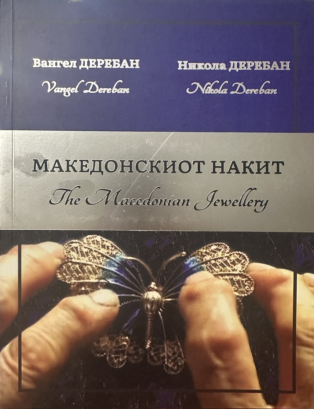 Корицата на „Македонскиот накит“ од Вангел и Никола Деребан, со рацете на Вангел што ја држат пеперутката на Александар